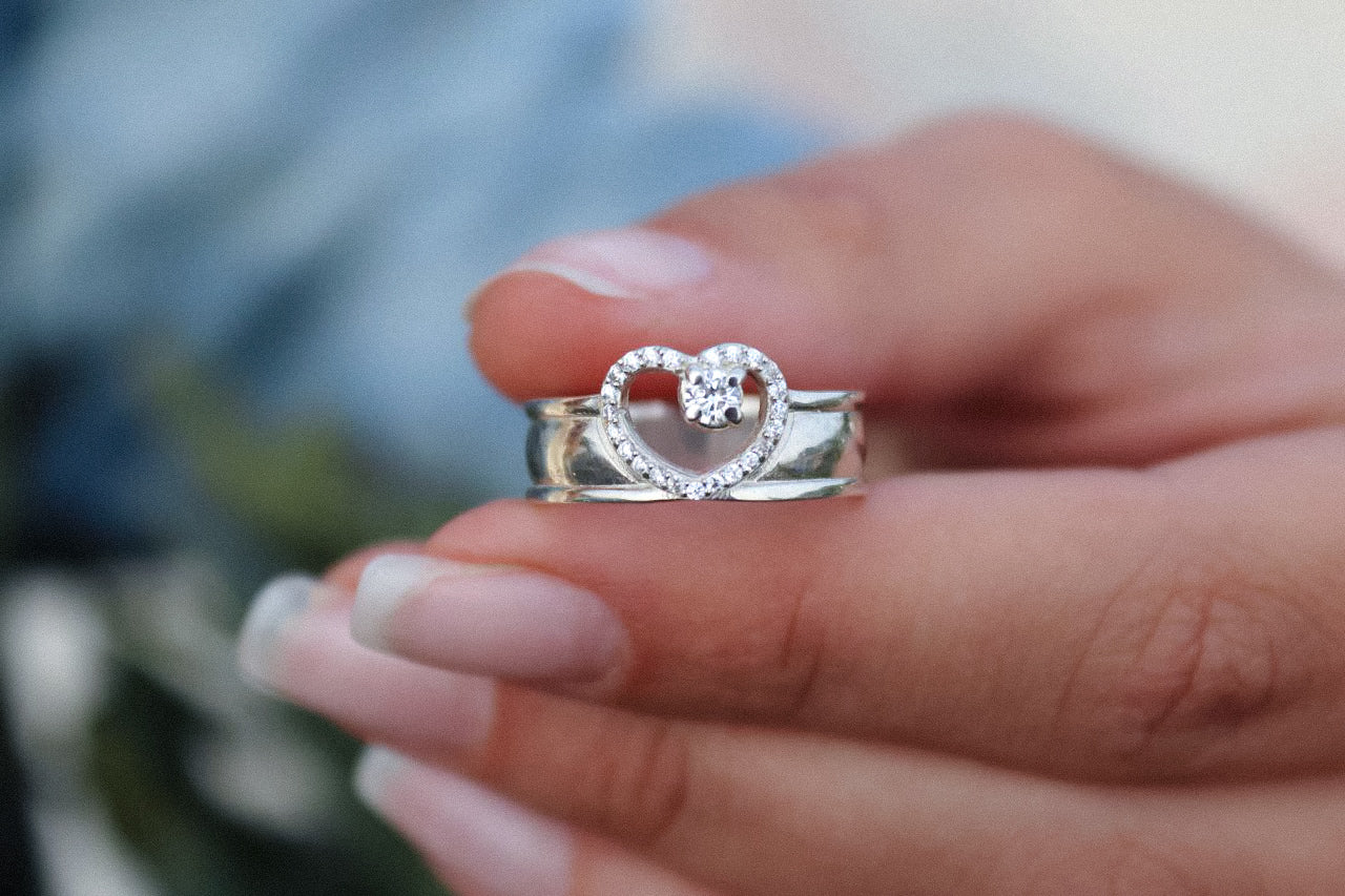 Introducing a charming ring with cubic zirconia stones laid out in the shape of a heart. The sparkling stones and interesting design make it an ideal choice for those who want to express their affection or simply add a touch of glamor to their outfit. 